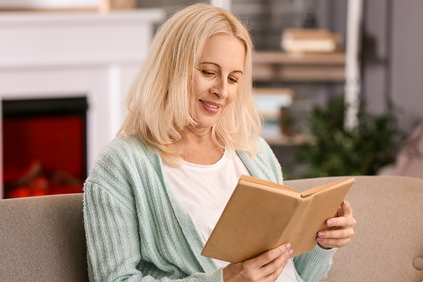 Beautiful mature woman reading book at home
